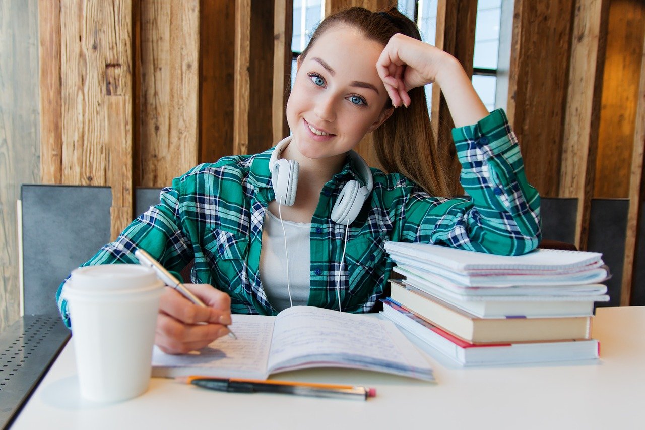 Happy teen girl at a desk with piles of papers