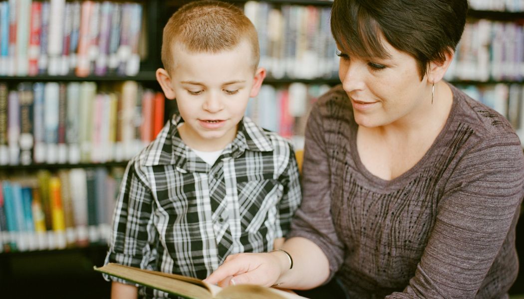 A teacher reading a book to a small boy