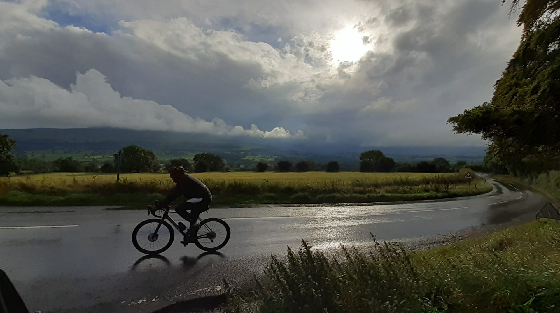Lone cyclist on an English country road passing beautiful scenery.