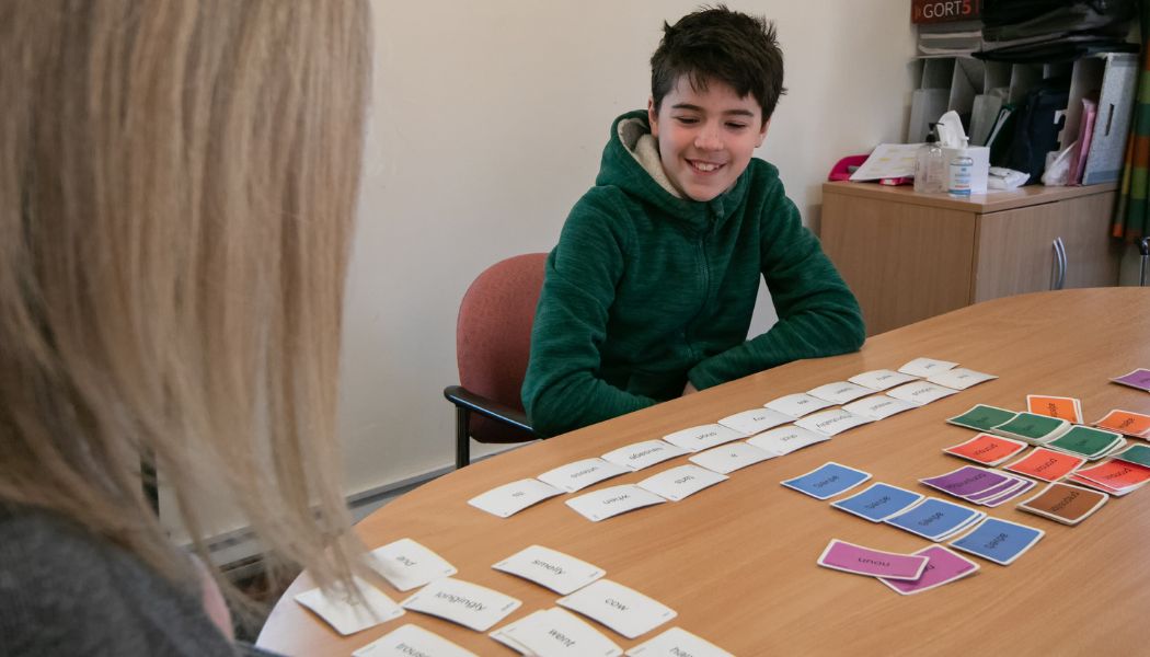 Boy and a teacher sit playing a word game at a table