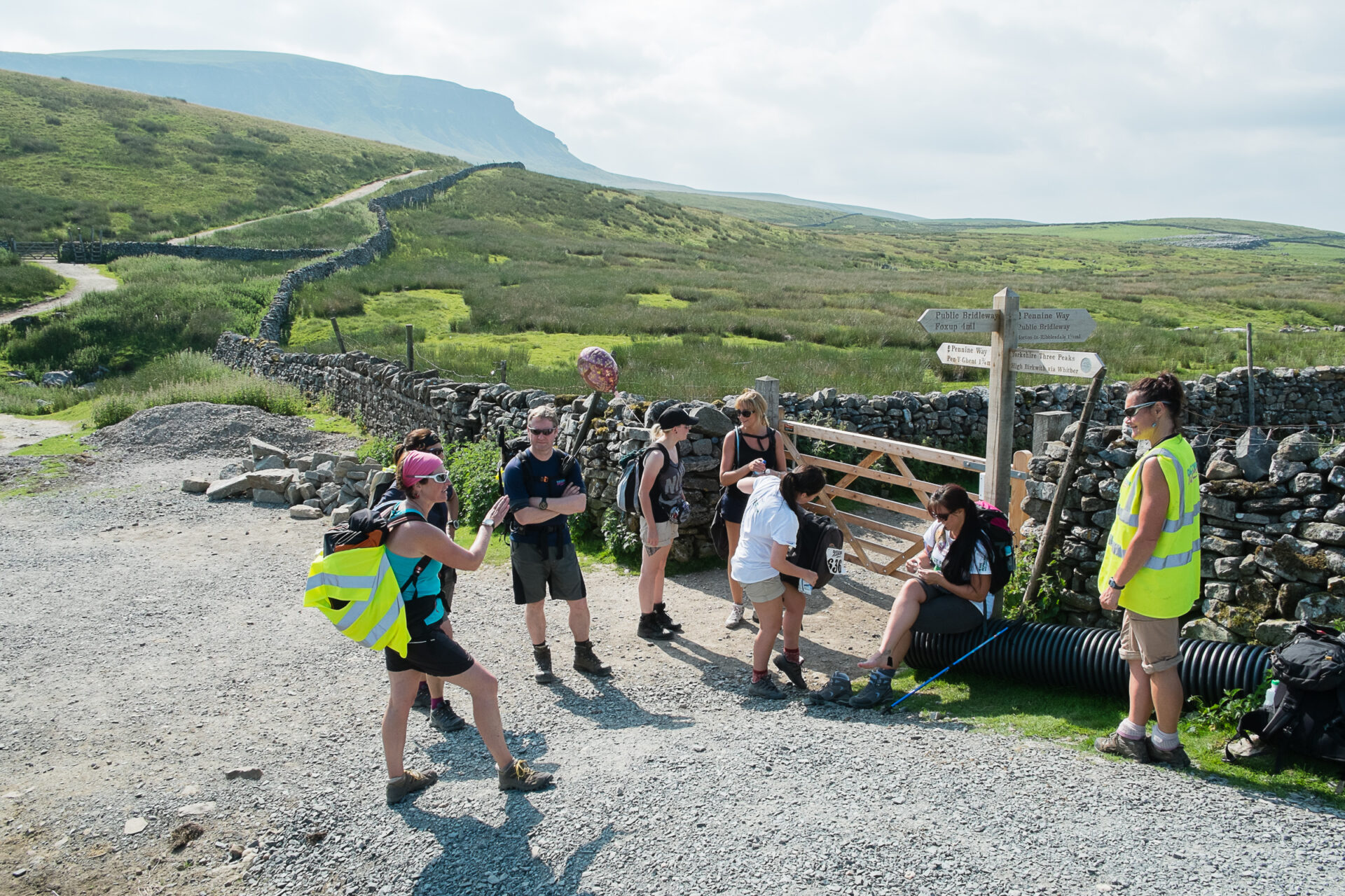 Hikers in Yorkshire Dales resting by a stile with beautiful scenery behind them.