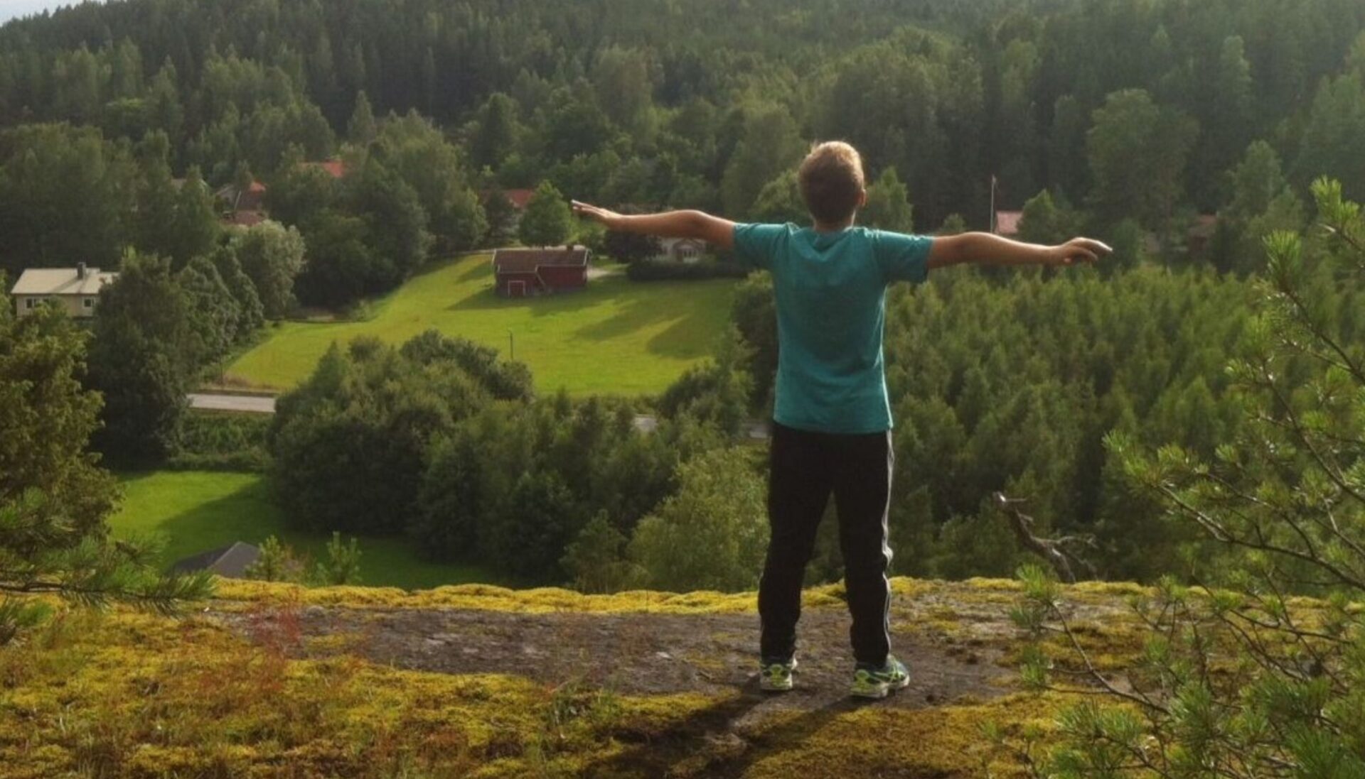 Boy with his arms open looking over a valley