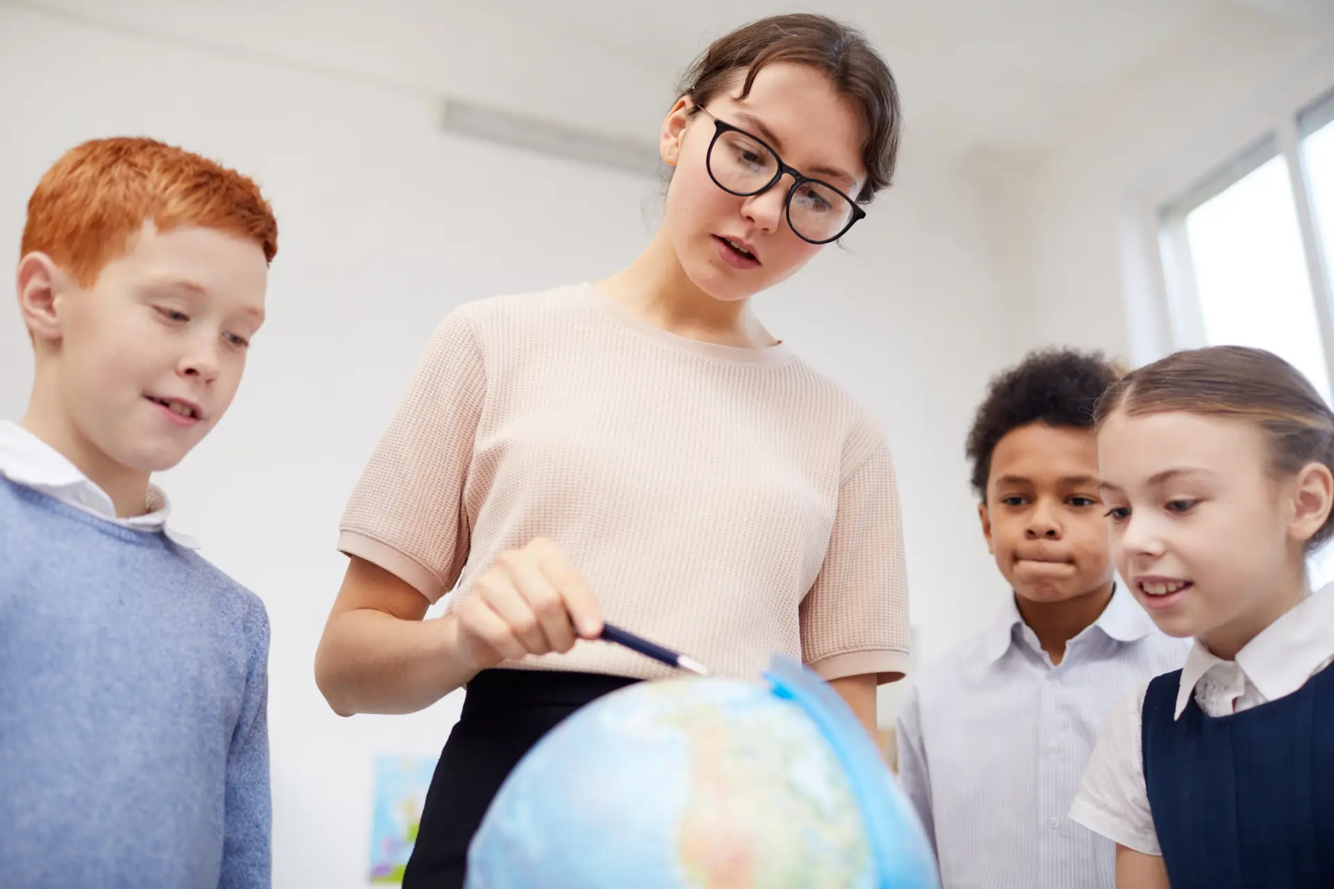 teacher-showing-the-globe-to-children A teacher showing some young students a globe